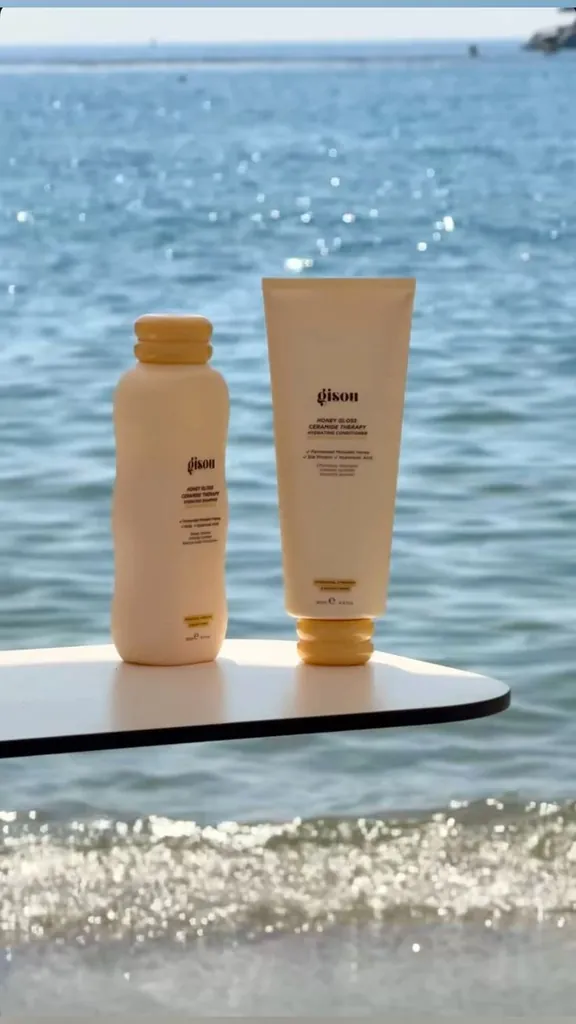 Two beige skincare bottles standing on a board at the shoreline