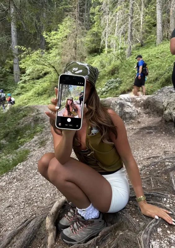 Person crouching on a forest trail filming with a phone